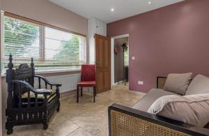 ein Wohnzimmer mit einem Bett, einem Stuhl und einem Fenster in der Unterkunft Villa 10 min bus to Oxford train in Oxford