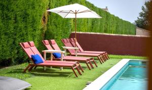 four chairs and an umbrella next to a swimming pool at Hôtel La Perna in Pernes-les-Fontaines