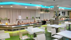 um restaurante com mesas brancas e cadeiras brancas em Hotel Las Vegas em Benidorm