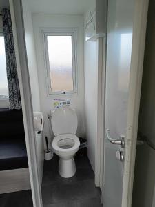a small bathroom with a toilet and a window at Mobilhome Indien in Oye-Plage