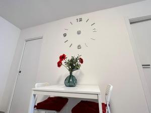 a vase with flowers on a white wall with a clock at i giardini di edicart in Bari