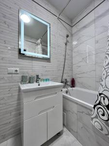 y baño con lavabo, bañera y espejo. en Gold Apartment Vysochana18, en Ivano-Frankivsk