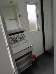 a small bathroom with a sink and a window at Mobilhome Indien in Oye-Plage