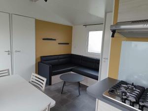 uma sala de estar com um sofá e um fogão em Mobilhome Indien em Oye-Plage