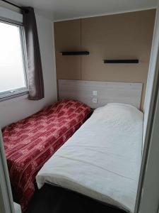 un piccolo letto in una piccola stanza con finestra di Mobilhome Indien a Oye-Plage