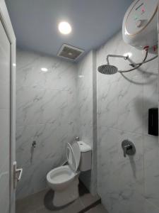 a white bathroom with a toilet and a shower at Horas Hotel in Sibolga