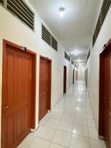 a hallway with brown doors and a tile floor at Horas Hotel in Sibolga