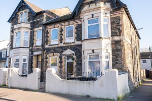 a brick house with a white fence in front of it at Stylish 2 Bedroom - Church View 3 by Tŷ SA in Newport