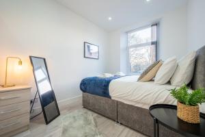 a bedroom with a bed and a table and a window at Stylish 2 Bedroom - Church View 3 by Tŷ SA in Newport