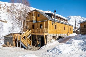 a wooden cabin in the snow with snow on the ground at Guesthouse Ushguli Maspindzeli in Ushguli