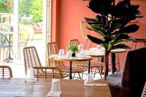 a restaurant with tables and chairs and a potted plant at Hôtel La Perna in Pernes-les-Fontaines