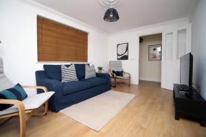 a living room with a blue couch and a tv at The Nook by Tŷ SA - Near Bike Park Wales in Nelson