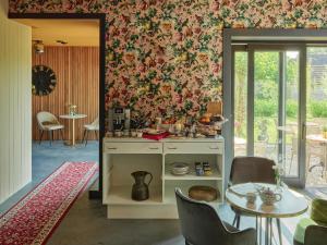 a kitchen with a table and a wall with floral wallpaper at B&B De Pastorie bij Dokkum in Reitsum