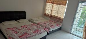 una camera da letto con due letti e una finestra di MAIDEEN HOMESTAY CAMERON HIGHLANDS a Brinchang