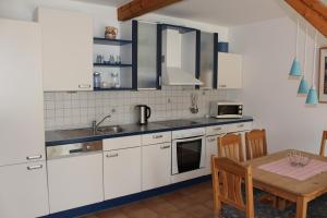 een keuken met witte kasten en een houten tafel bij Ferienhof " Dat grode Gulfhuus" in Tossens +5 foto's