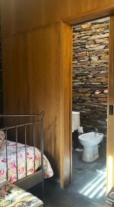- une chambre avec un lit et un lavabo dans un mur en pierre dans l'établissement Casa da Azenha - Casas da Paradinha com praia fluvial, à Paradinha