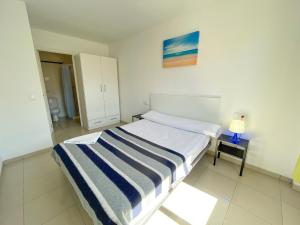 a bedroom with a bed with a blue and white striped blanket at Apartamentos Playa de Benicarló 3000 in Benicarló +77 photos