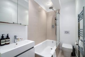 GuestReady - Family-Friendly Flat in Battersea في لندن: حمام أبيض مع حوض ومرحاض