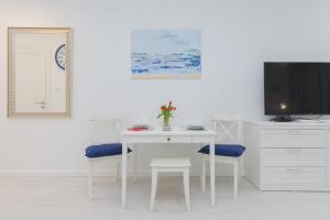 a white dining room with a white table and chairs at Rogowo Pearl Apartament z Tarasem Od Strony Morza by Renters in Rogowo