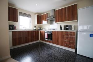 uma cozinha com armários de madeira e um frigorífico branco em Upper Millennium by Tŷ SA - Free Parking em Newport