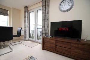 a living room with a television and a clock on the wall at Upper Millennium by Tŷ SA - Free Parking in Newport