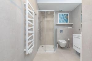 a white bathroom with a shower and a toilet at Rogowo Pearl Apartament z Tarasem Od Strony Morza by Renters in Rogowo