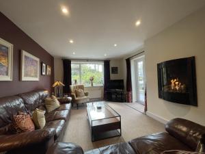 a living room with a leather couch and a fireplace at Pinecroft in Keswick