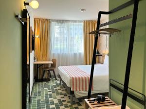 a hotel room with a bed and a desk and a mirror at Nonanteneuf Appart-hôtel - Sierre in Sierre