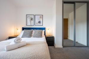 Schlafzimmer mit einem Bett mit blauem Kopfteil und einem Spiegel in der Unterkunft Waterside by Tŷ SA -Free Parking in Cardiff