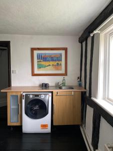 uma cozinha com uma máquina de lavar roupa e um lavatório em The Kentford em Kentford