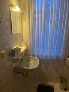 a white bathroom with a sink and a window at Maccaroni Restaurants & Hotels in Meiningen