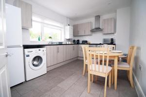 a kitchen with a table and a washing machine at Willow Way by Tŷ SA in Nantgarw