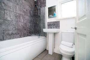 a bathroom with a tub and a toilet and a sink at Willow Way by Tŷ SA in Nantgarw