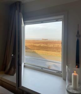 a window with a candle and a view of the beach at Walters Hof Kampen in Kampen