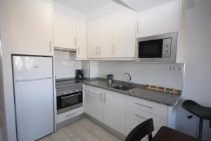 una cocina blanca con armarios blancos y fregadero en Apartamentos Tramuntana42, en Roses