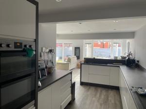 a kitchen with white cabinets and a living room at North East Escape in Holystone