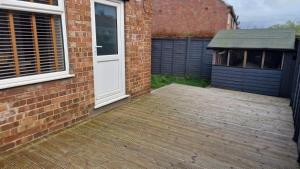 a wooden deck next to a brick building with a door at Designed Gem in Cayton