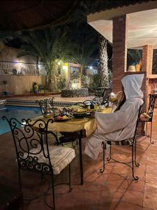 een eettafel en stoelen met eten erop naast een zwembad bij Riad le petit jardin in Zagora