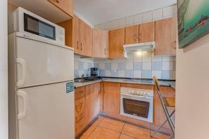 een keuken met een witte koelkast en houten kasten bij Ocean view Agua Marina 1 bedr apartment in San Miguel de Abona