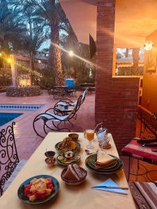 - une table avec des assiettes de nourriture sur une terrasse dans l'établissement Riad le petit jardin, à Zagora