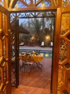 comedor con mesa y piscina en Riad le petit jardin, en Zagora
