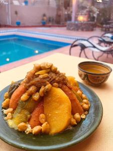 une assiette de nourriture sur une table à côté d'une piscine dans l'établissement Riad le petit jardin, à Zagora