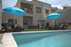a swimming pool with two blue umbrellas and a house at Villa Sunview in Rabat