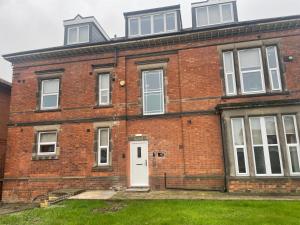 an old brick building with a white door at Luxury Central Derby Apartment in Derby