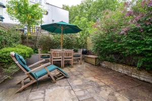 a patio with a table and chairs and an umbrella at GuestReady - Family Stay in the heart of Fulham in London