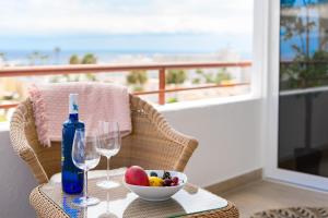 a table with a bowl of fruit and a bottle of wine at GREEN AGAVE by Welcome Tenerife in Playa de las Americas