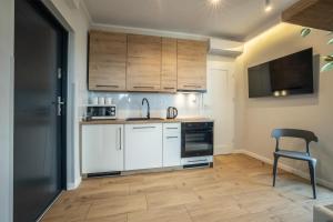 uma cozinha com armários brancos e uma cadeira em WiguryTower Apartaments 92 em Lódź