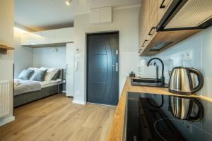 uma cozinha com um lavatório e uma cama num quarto em WiguryTower Apartaments 92 em Lódź