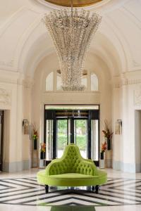 a large lobby with a green bench in front of a chandelier at Waldorf Astoria Versailles - Trianon Palace in Versailles