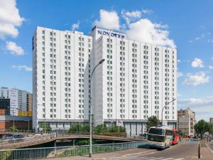 un bâtiment blanc avec un bus devant lui dans l'établissement Novotel Paris Est, à Bagnolet